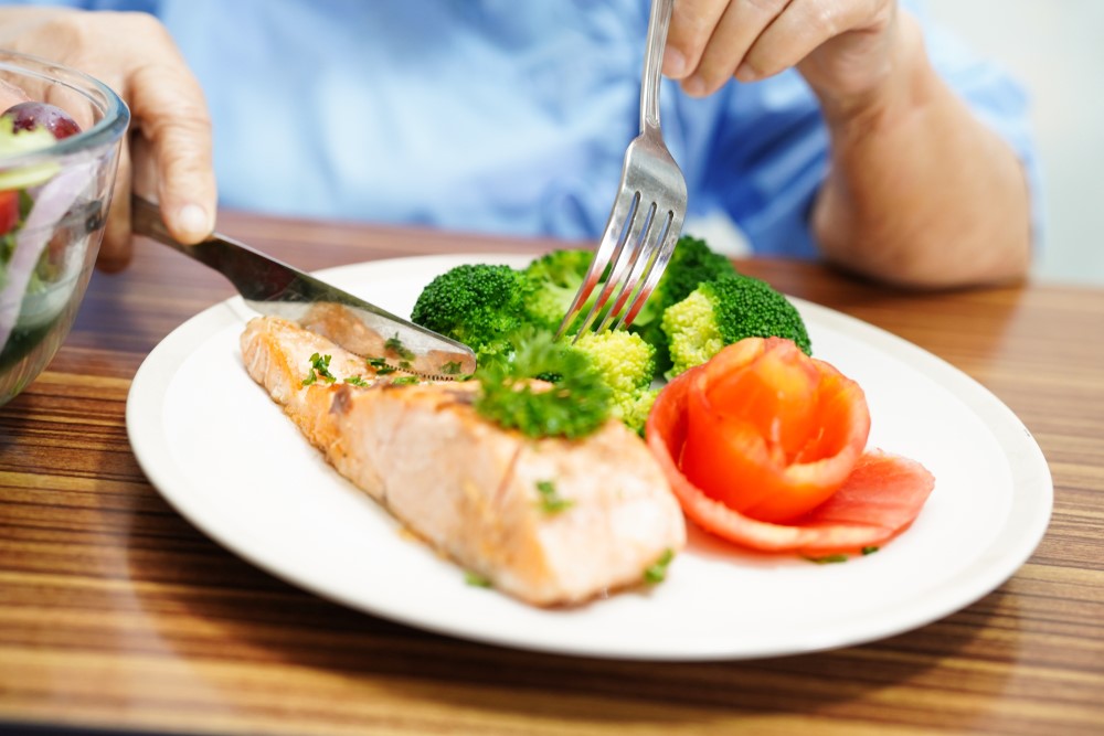 A senior cutting a healthy meal on a plate