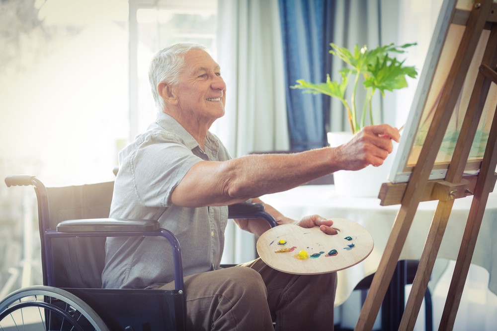 A senior in a manual wheelchair painting