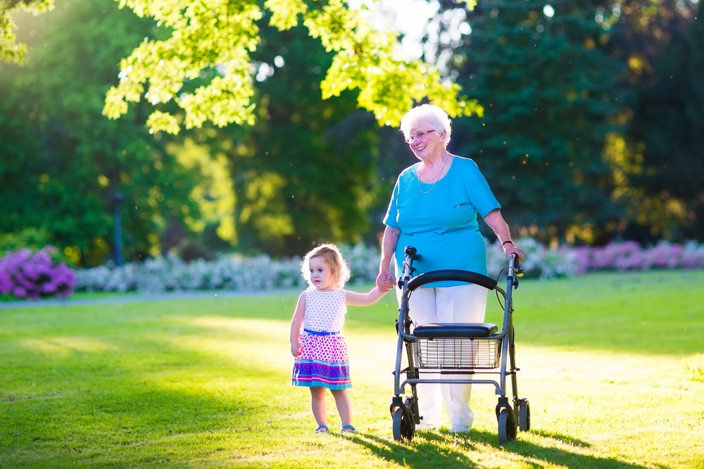 A senior woman using a rollator and holding her grand daughter's hand