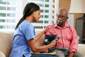 An elderly African American man having his blood pressure checked at home, highlighting the idea of Americans managing healthcare as expats