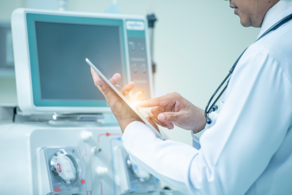 A doctor holding a pad next to a dialysis machine