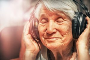 A happy senior woman using headphones, highlighting the idea of tech gifts for seniors