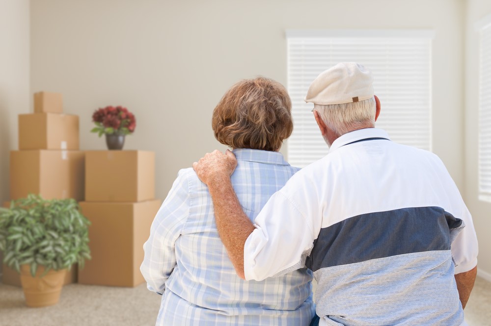 A senior couple with all their things packed up in boxes, highlighting the idea of moving in with family members