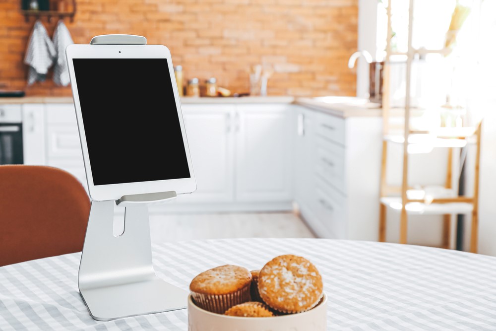 A tablet in a tablet holder in a brightly lit kitchen