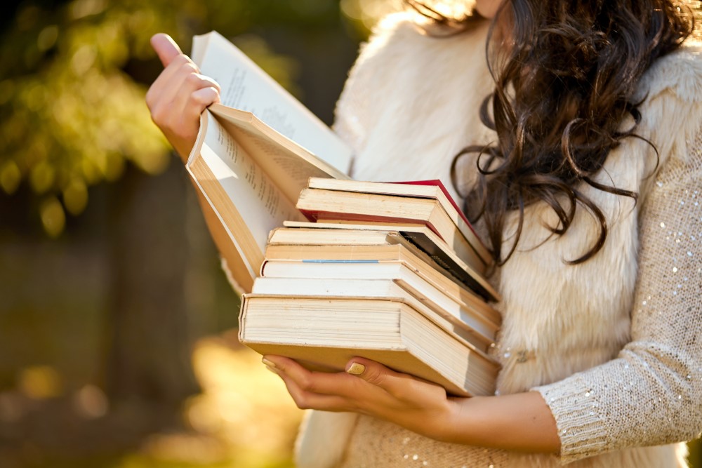 A woman reading a stack of books