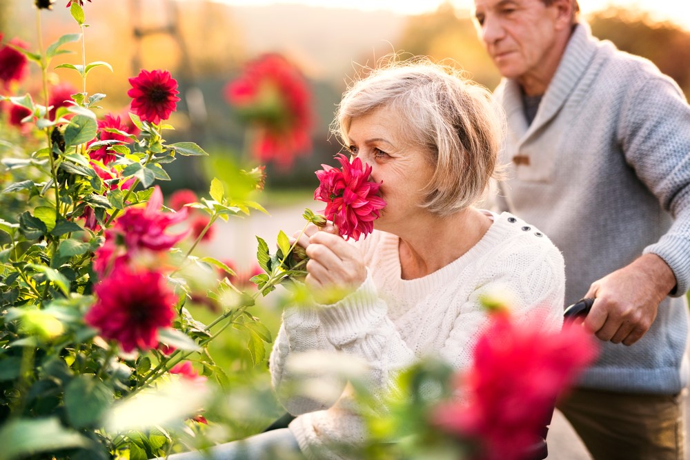 An interabled couple where the woman is smelling flowers