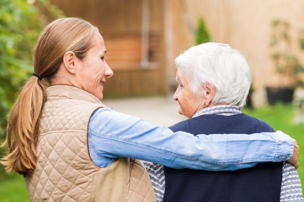 A family member walking with a senior in their retirement community