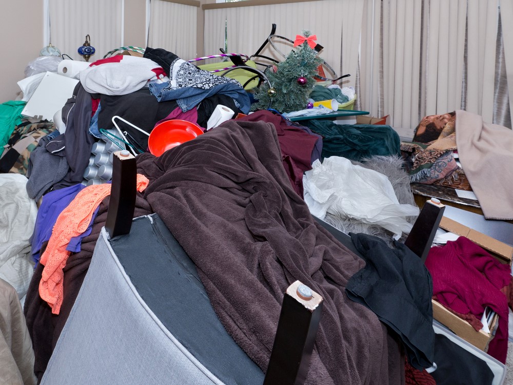 A bedroom filled with hoarded clothing and other items