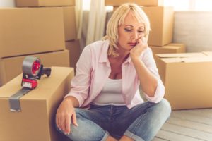 A sad caregiver with box tape, feeling the guilt of moving away from elderly parents