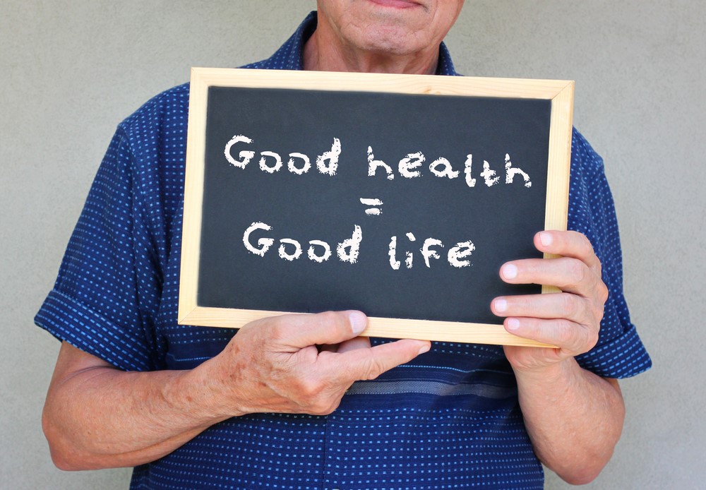 A senior holding a sign that talks about good health and good life