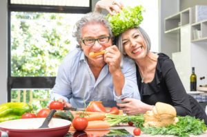 Two seniors having fun in the kitchen with plenty of healthy food, highlighting the idea of brain food for seniors