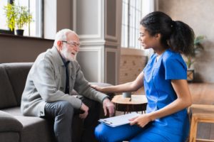 A young caregiver and an older man talking, highlighting the idea of how hiring a professional caregiver can make life easier and less stressful