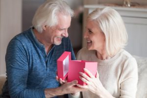 An older man giving his partner a romantic gift