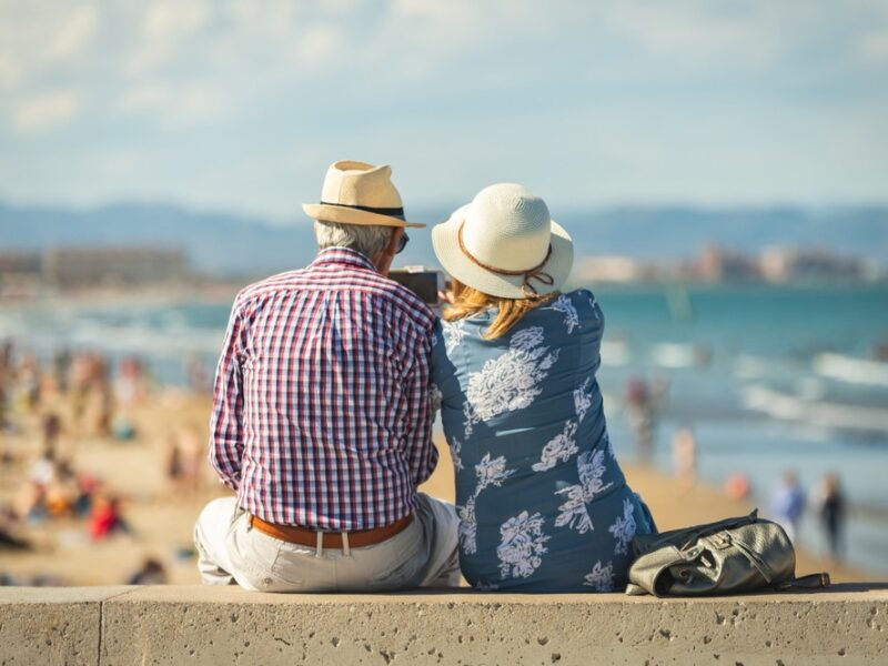 A senior couple sitting and looking out at a beach