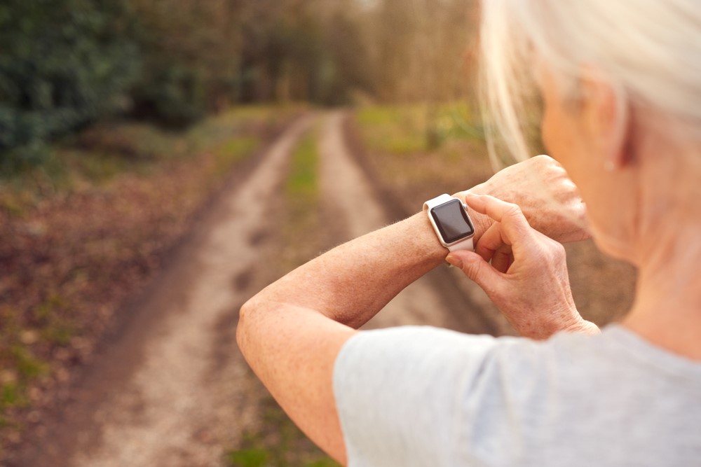A senior using a smartwatch before going on a run