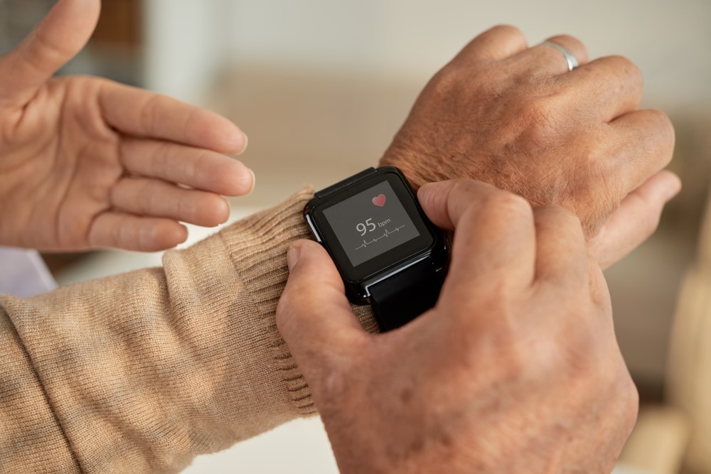 An elderly man being taught how to use a smartwatch