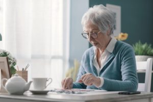 An elderly woman working on a puzzle, highlighting the idea of puzzles for dementia patients