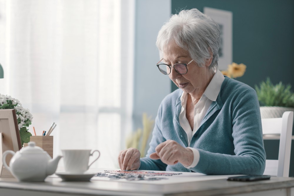 An elderly woman working on a puzzle, highlighting the idea of puzzles for dementia patients