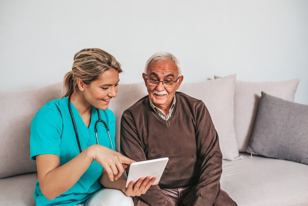 A caregiver and older gentleman sitting on a couch