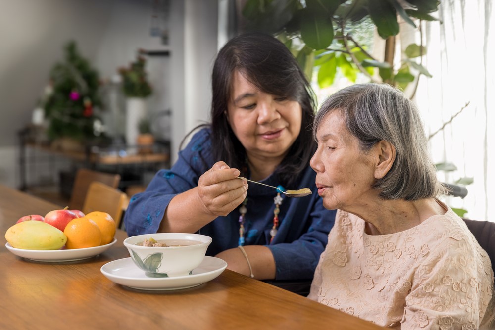 A caregiver helping an elderly woman to eat