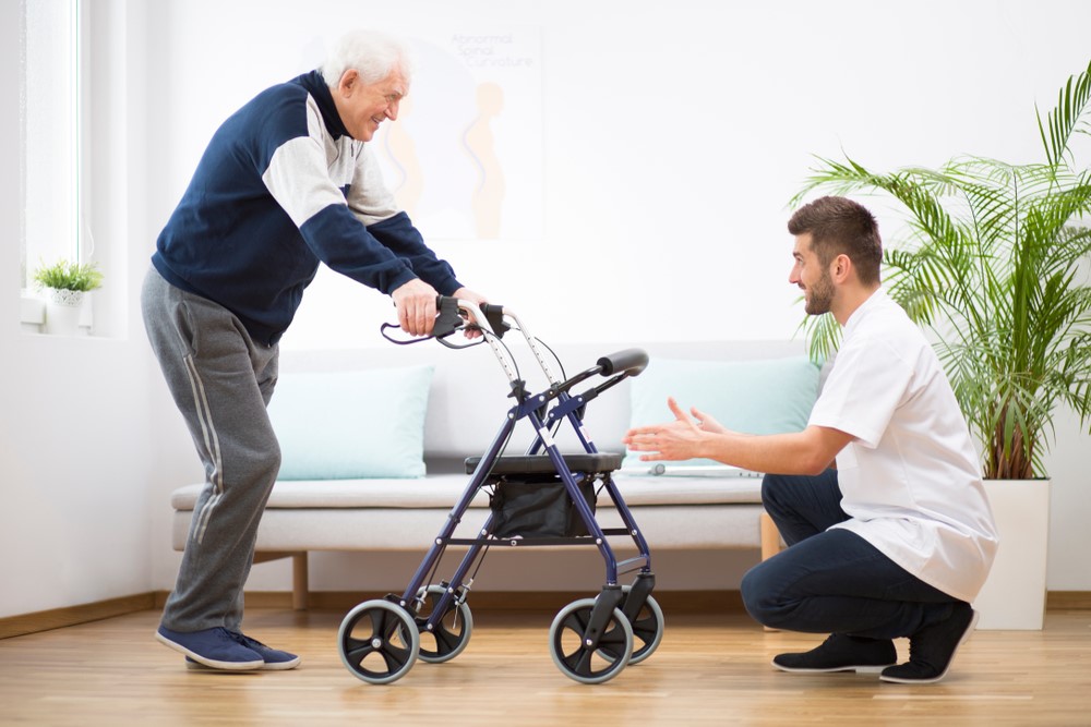 A senior and a caregiver working with a walker