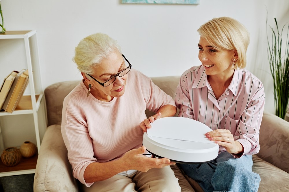 A senior and her daughter looking at a Roomba,, highlighting how AI can change life for seniors