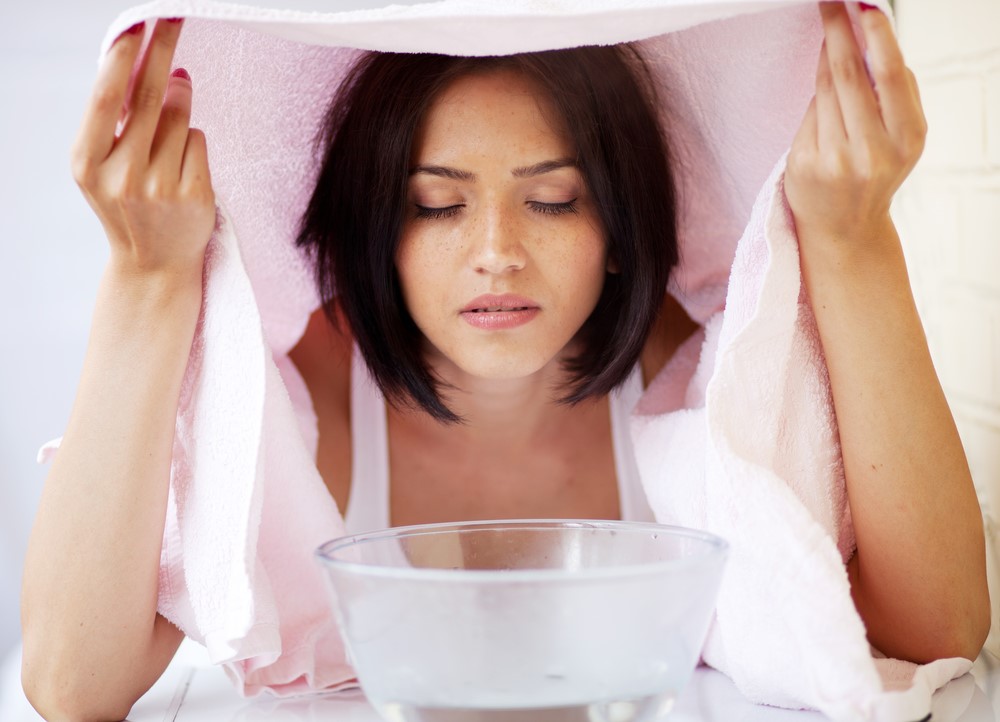 A young woman or caregiver using a steaming bowl with a towel