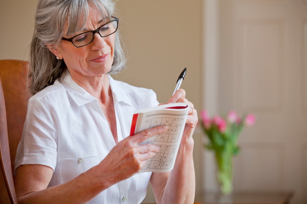 An elderly woman working on an activity book for seniors