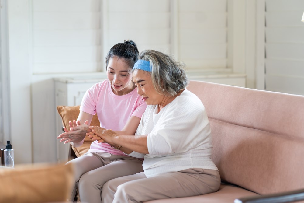 An older woman sitting on a couch next to her granddaughter, highlighting the idea of getting paid to care for a family member