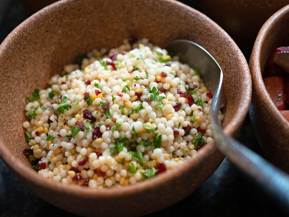 A brown bowl of large couscous grains