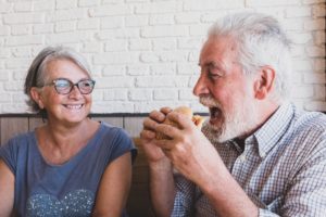 A senior couple enjoying themselves, where the man is eating a burger