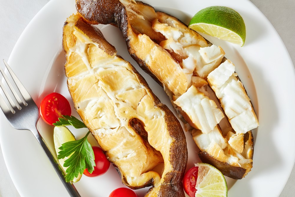 A white plate with two pieces of cooked fish