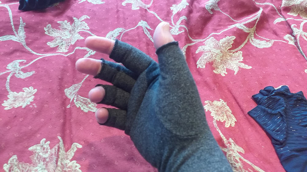 A gray Raynaud's compression glove against a red and blue background