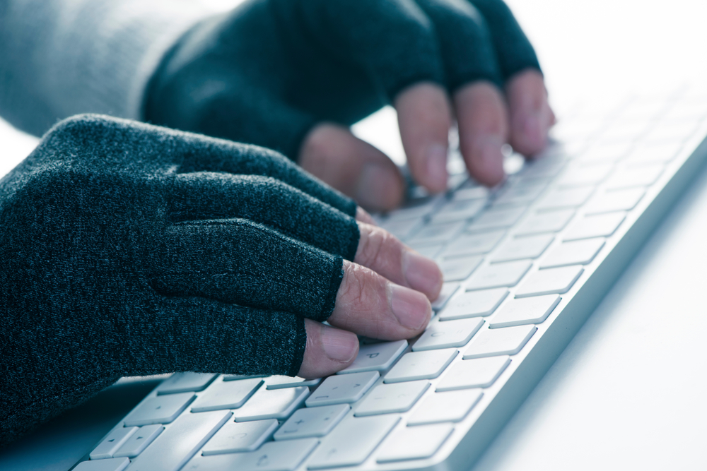 Someone typing wearing a pair of compression gloves, looking at whether Raynaud's compression gloves actually work