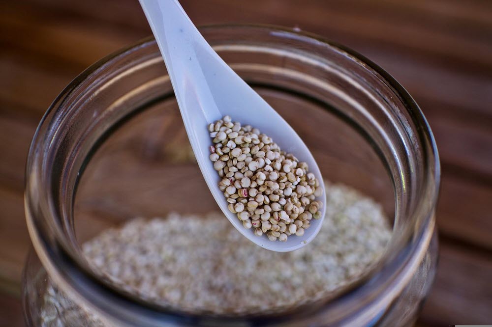 Uncooked quinoa being scooped out of a jar