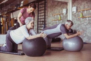 A gym trainer or an exercise physiologist working with two seniors