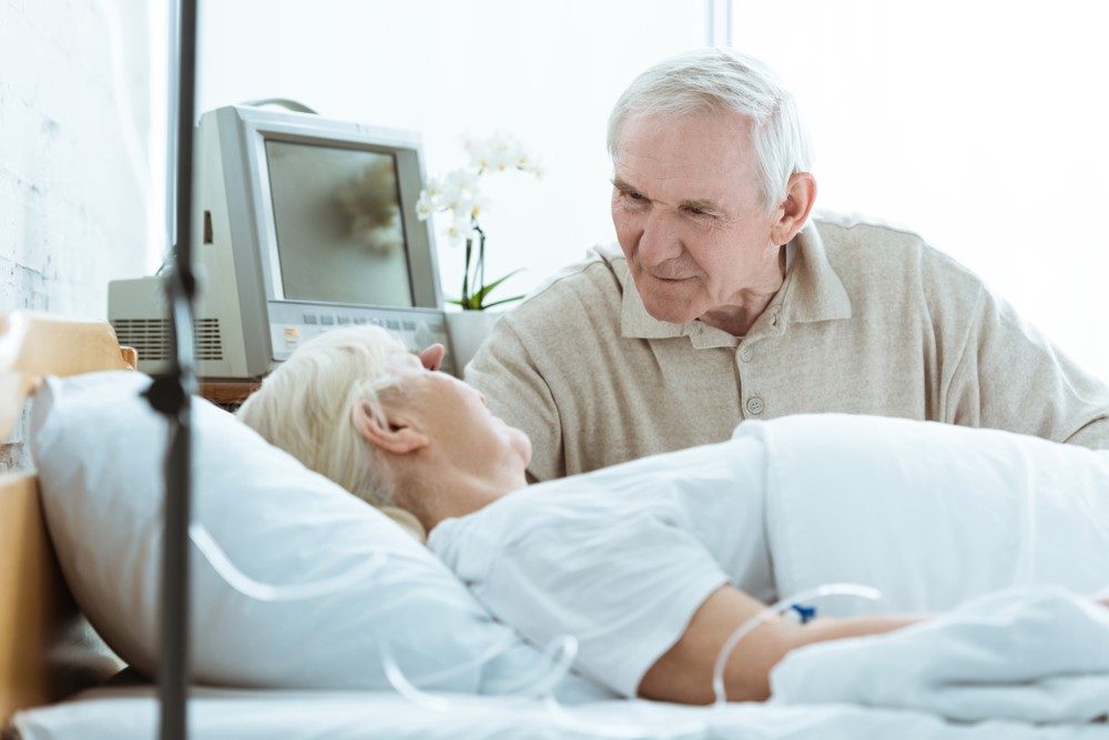 A senior man sitting with his ill wife