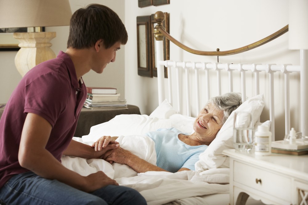 A woman being visited by her grandson in her bed at home