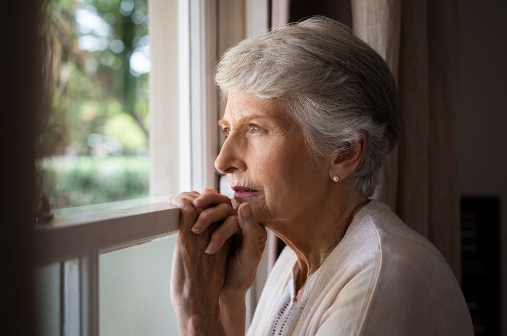 A sad elderly woman looking outside