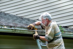 A senior cleaning gutters, highlighting the idea that my aging father does too much