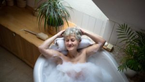 A woman laid back in the bath, highlighting the power of bath accessories for seniors