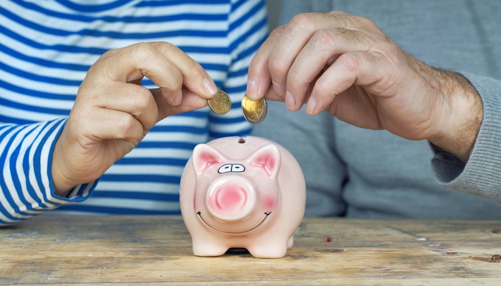 Two seniors saving money with a piggy bank