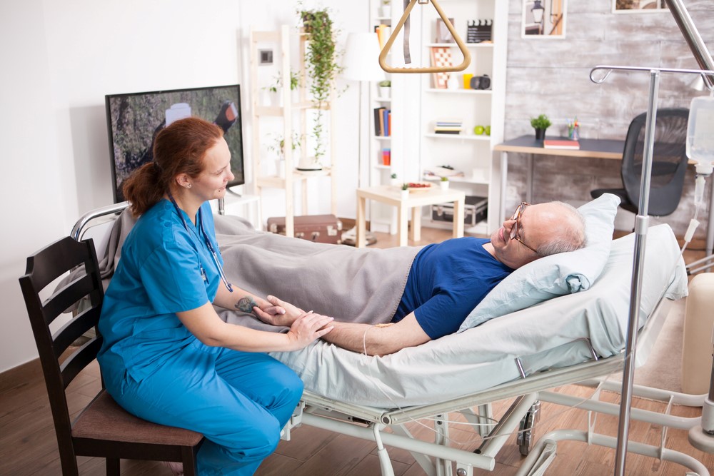 A medical bed that has been set up at home, with a staff member providing hospice at home services, highlighting the strengths and challenges of dying at home