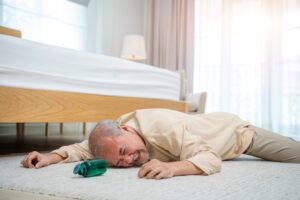 A senior man who has fallen on the floor, highlighting the question of how to stop seniors falling out of bed