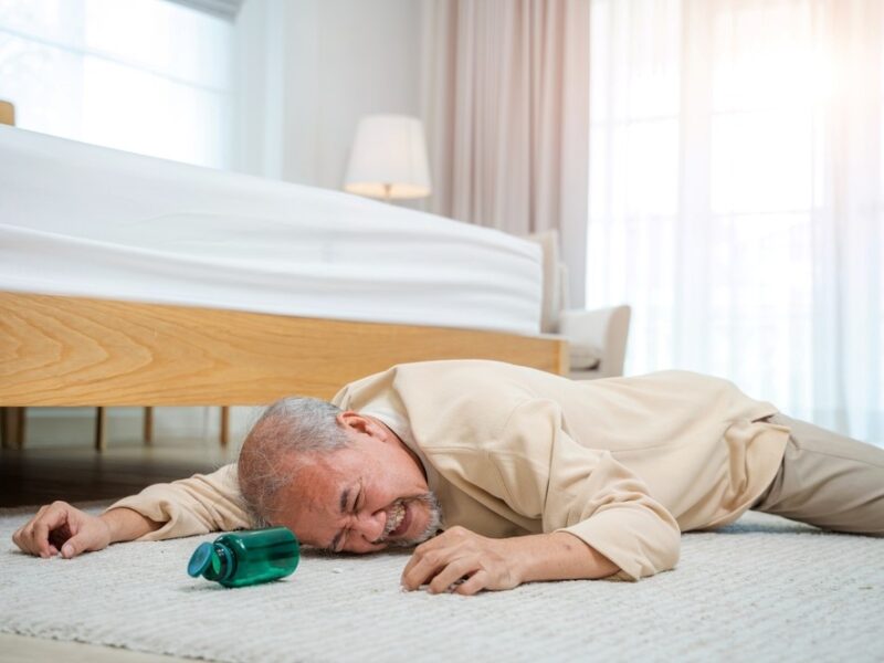 A senior man who has fallen on the floor, highlighting the question of how to stop seniors falling out of bed