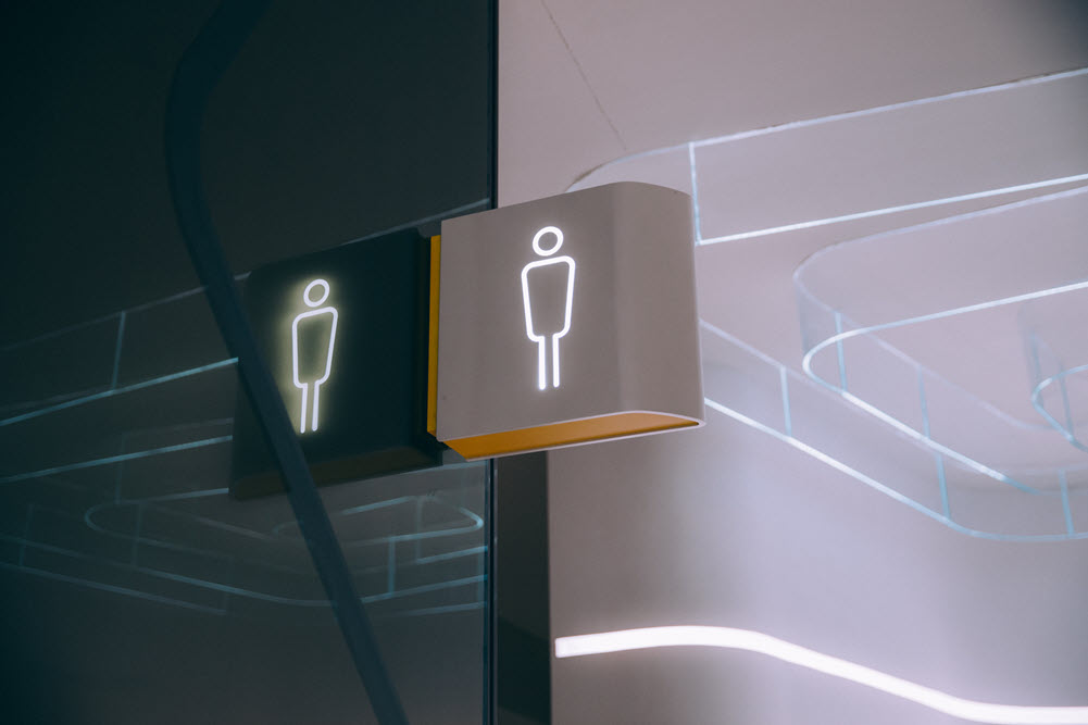 A modern bathroom sign for men, highlighting the concept of incontinence questions