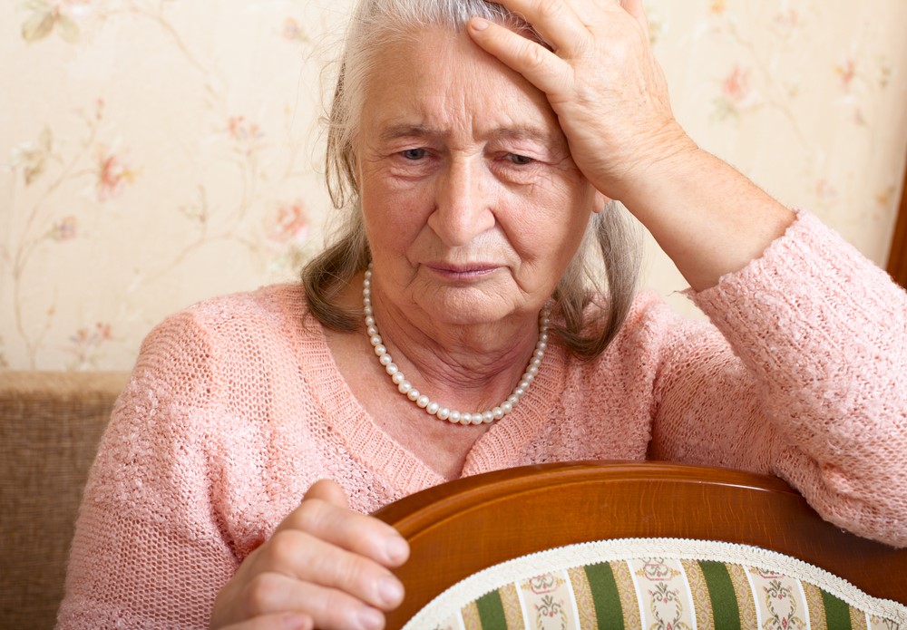 A senior leaning on a chair looking upset