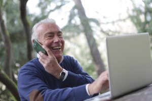 An older man looking at his computer screen while on the phone