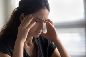 A stressed caregiver with her hands to her head, highlighting the idea of caregiver martyr syndrome