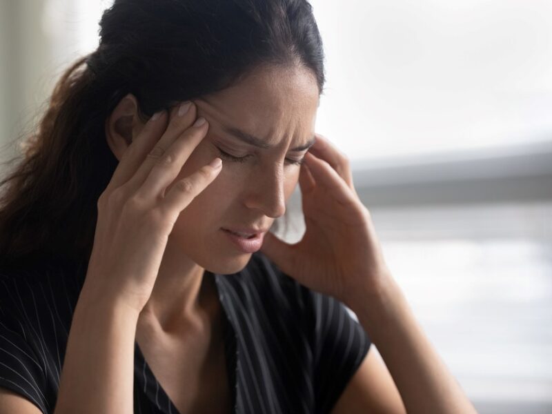 A stressed caregiver with her hands to her head, highlighting the idea of caregiver martyr syndrome